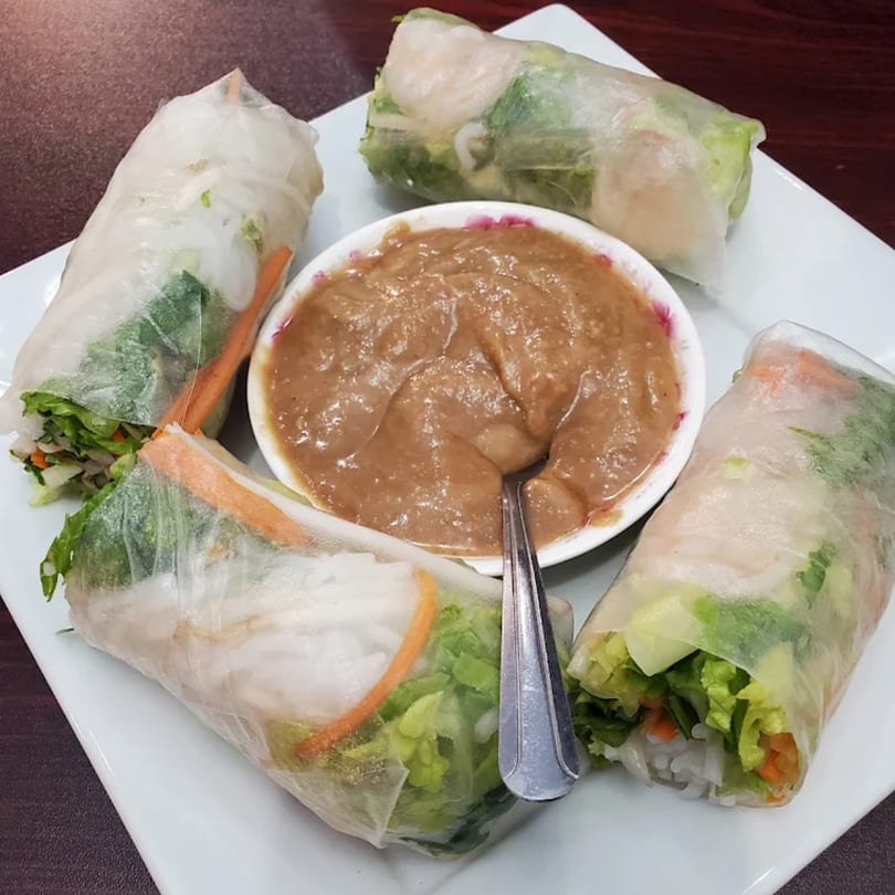 Four fresh Thai spring rolls with shrimp and vegetables, served with a peanut dipping sauce.