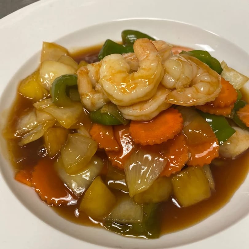 Sweet and sour shrimp with bell peppers, carrots, and pineapple in a brown sauce.