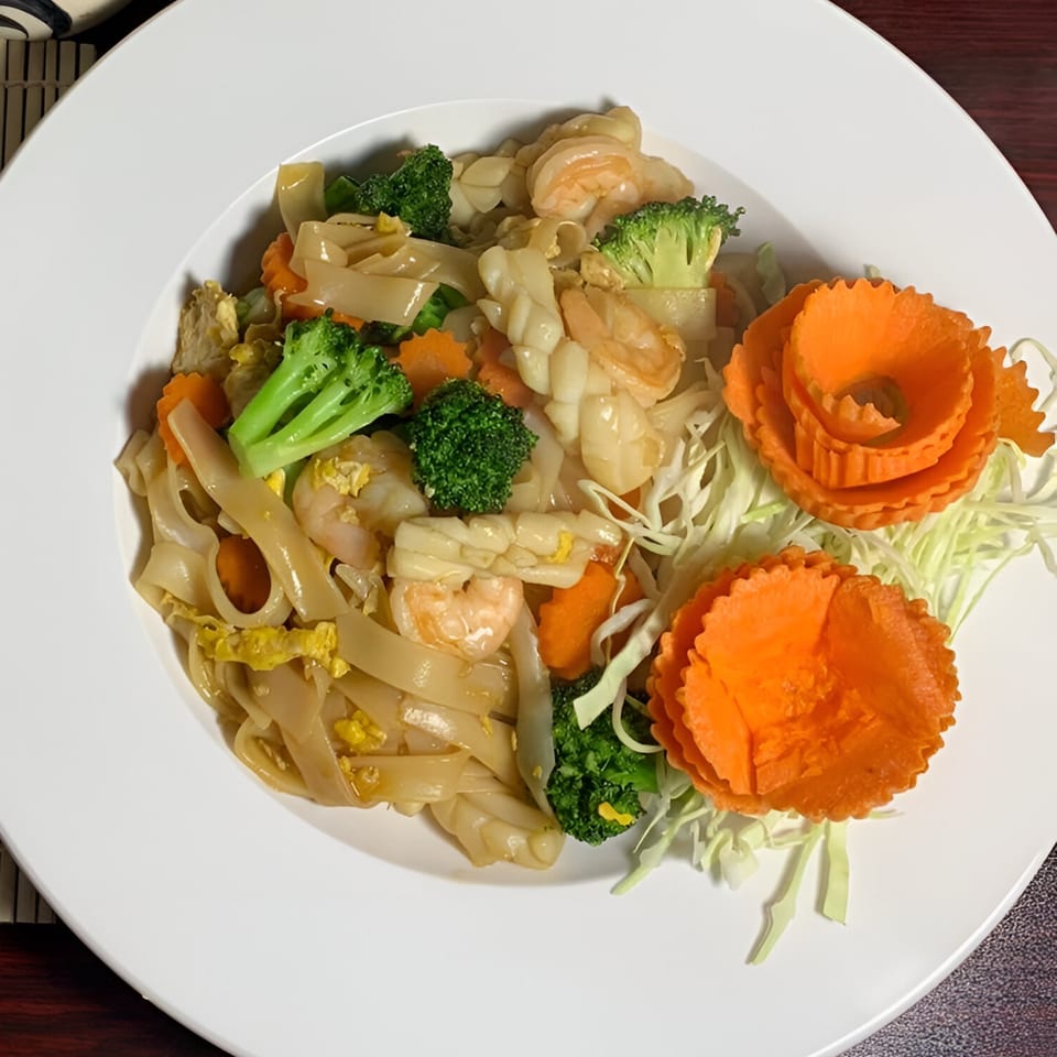 Thai Pattaya Restaurant's Pad See Ew with shrimp, squid, broccoli, carrots, and decorative carrot flowers.