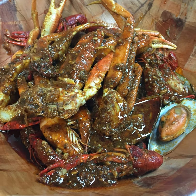 A close-up of Thai Pattaya's seafood boil with crabs, crawfish, and mussels in a rich, dark sauce.